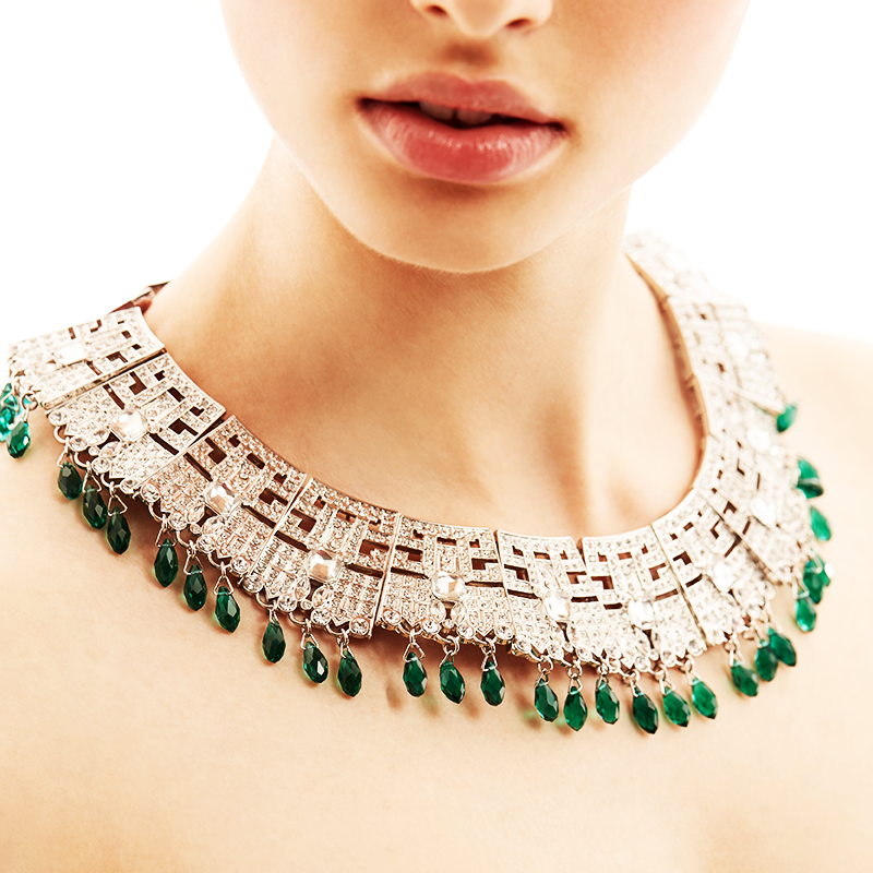 Close-up of LAMA necklace worn on neckline with green crystal drops