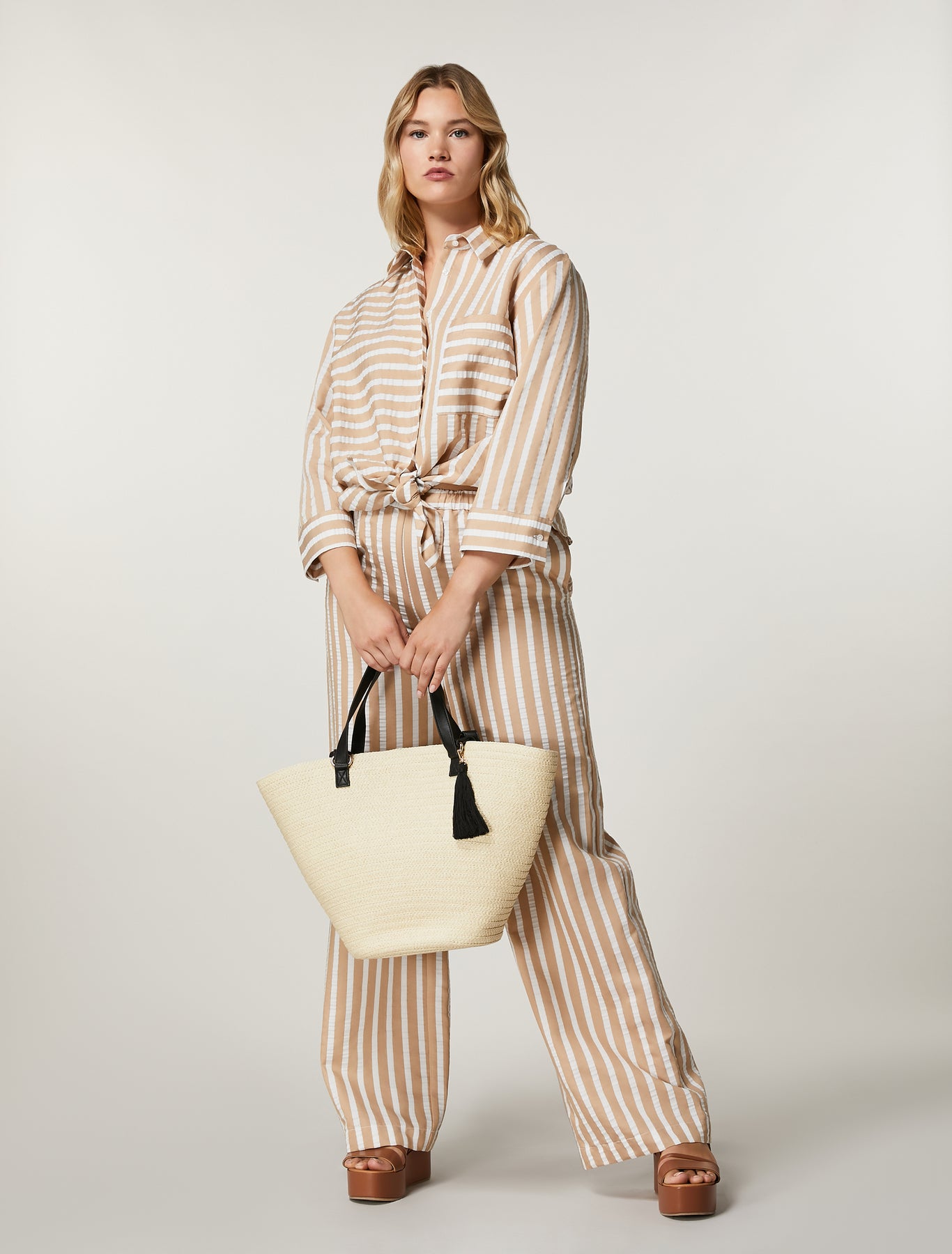 Model wearing full striped set with ALABAMA blouse tied at waist and CRISMA trousers