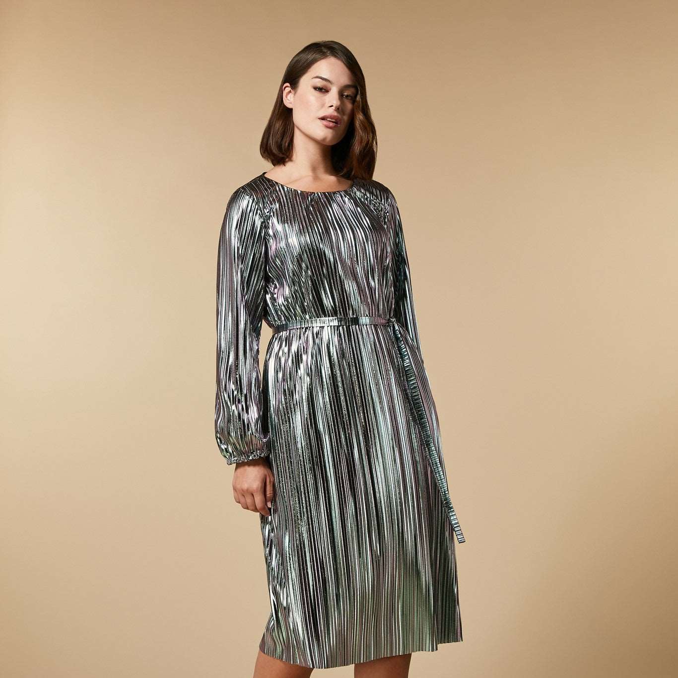 Midi dress made of shimmering pleated fabric. The relaxed garment has a round neckline and is adorned with elastic cuffs on the wide long sleeves. The fit can be adjusted at the waist with a suitable belt. This model adds a sparkling touch to your important event attire.