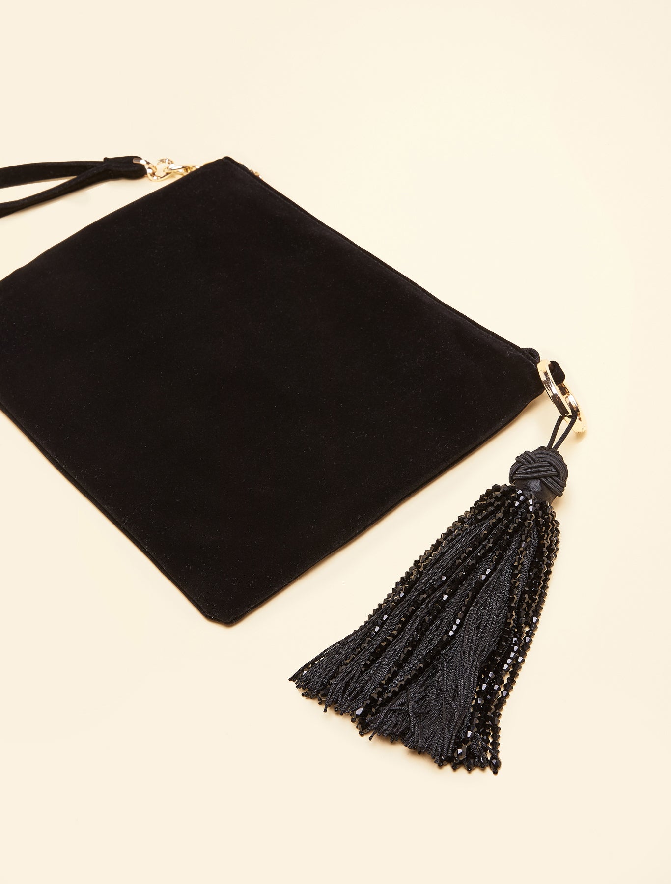 Velvet clutch with zip closure and beaded tassel laid flat