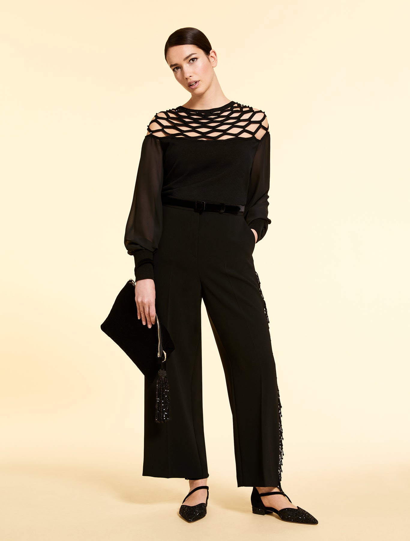 Model holding the SAHARA black velvet clutch with tassel pendant