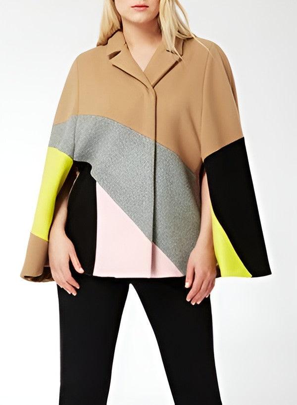 A woman wearing a color-blocked cape jacket with tan, gray, black, light pink, and neon yellow panels, paired with black pants, against a plain white background.