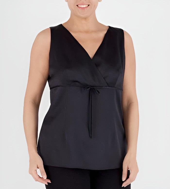 A woman wearing a sleeveless black wrap-style top with a V-neckline and a drawstring tie at the waist, shown against a plain light gray studio background.