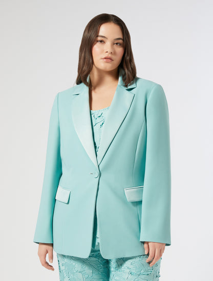 Model wearing a mint-colored "ARPE" blazer made of lightweight fabric, fully lined, with a single button closure and notched lapels