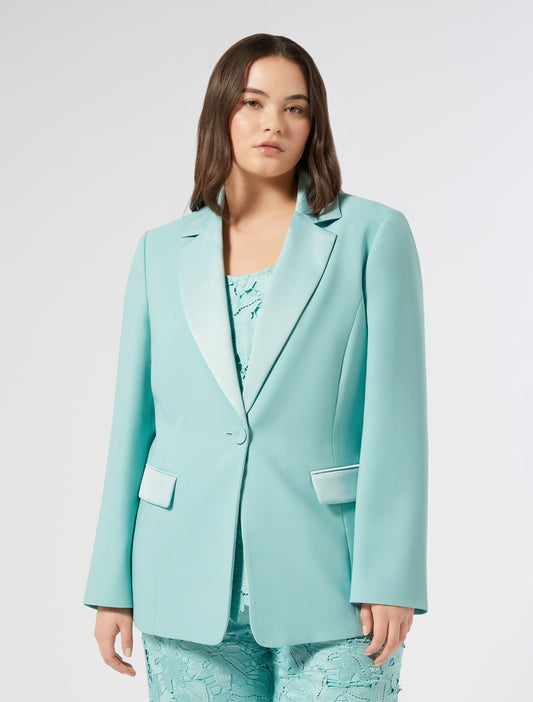 Model wearing a mint-colored "ARPE" blazer made of lightweight fabric, fully lined, with a single button closure and notched lapels
