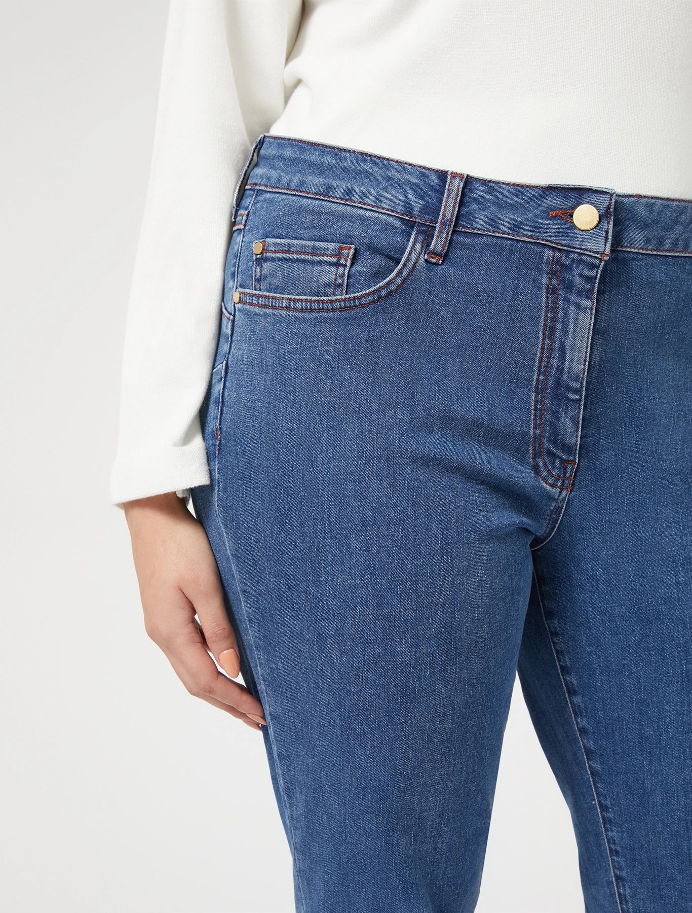 Close-up of button and front pockets, dark blue denim