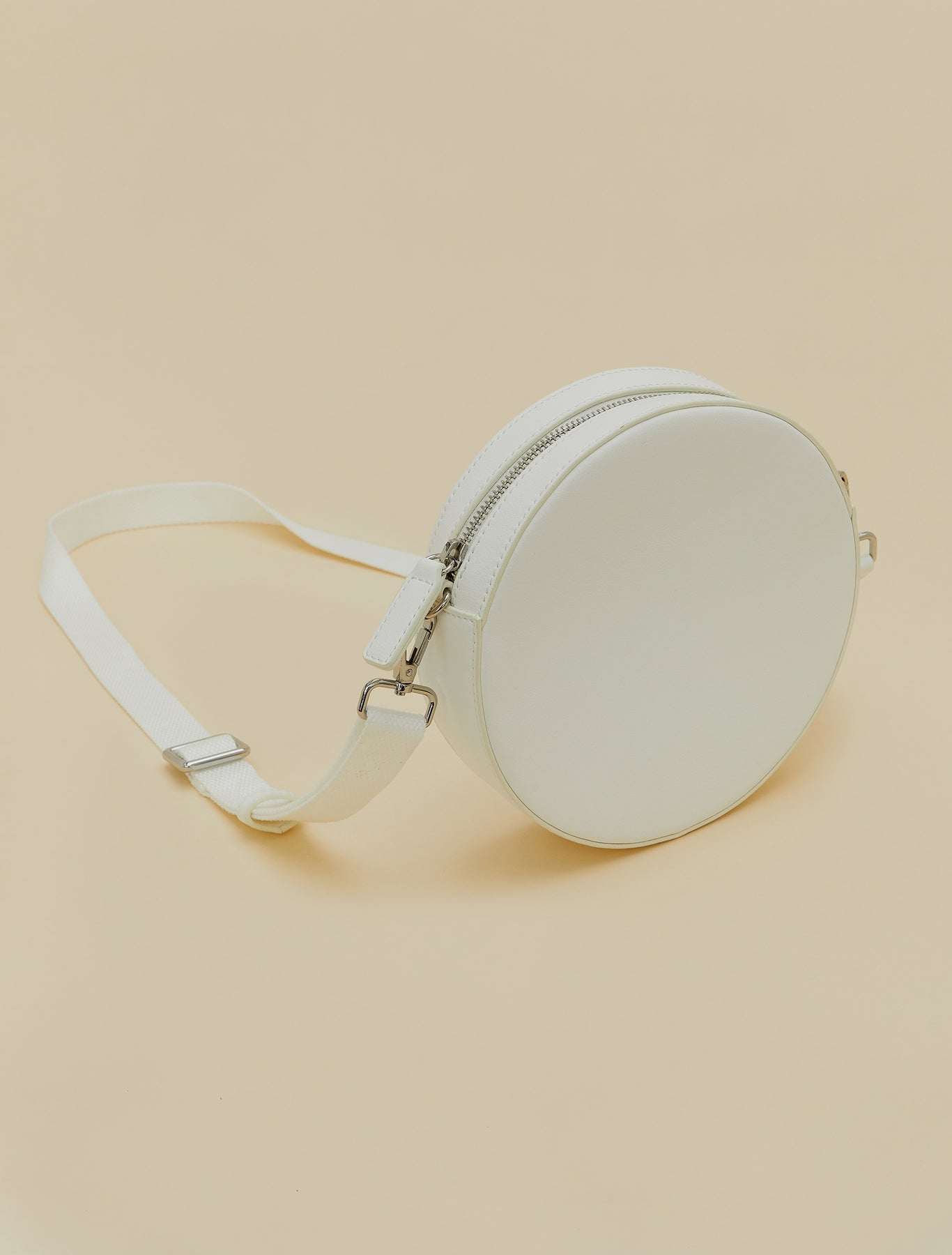 Covered fabric round bag with removable strap, zipper, and inner pocket, wearable as crossbody or waist bag