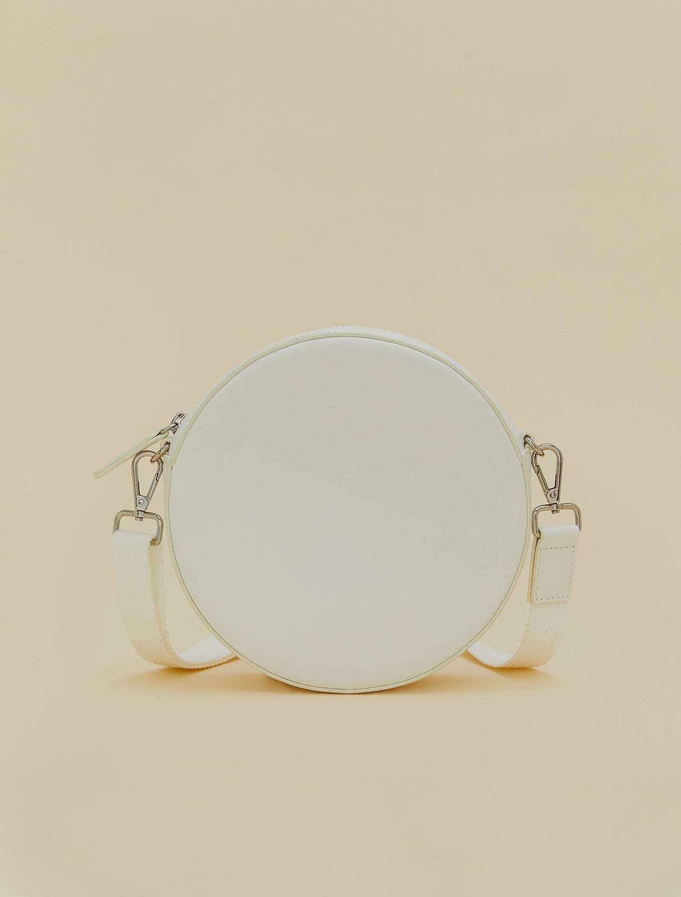 Covered fabric round bag with removable shoulder strap, zipper, and inner cotton-lined pocket.