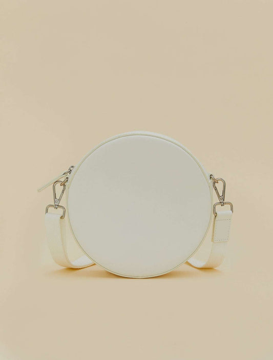 Covered fabric round bag with removable shoulder strap, zipper, and inner cotton-lined pocket.