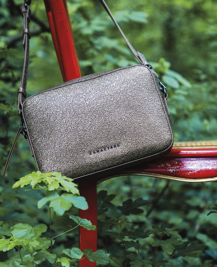 Silver leather crossbody bag by Caractère with shoulder strap, photo in greenery